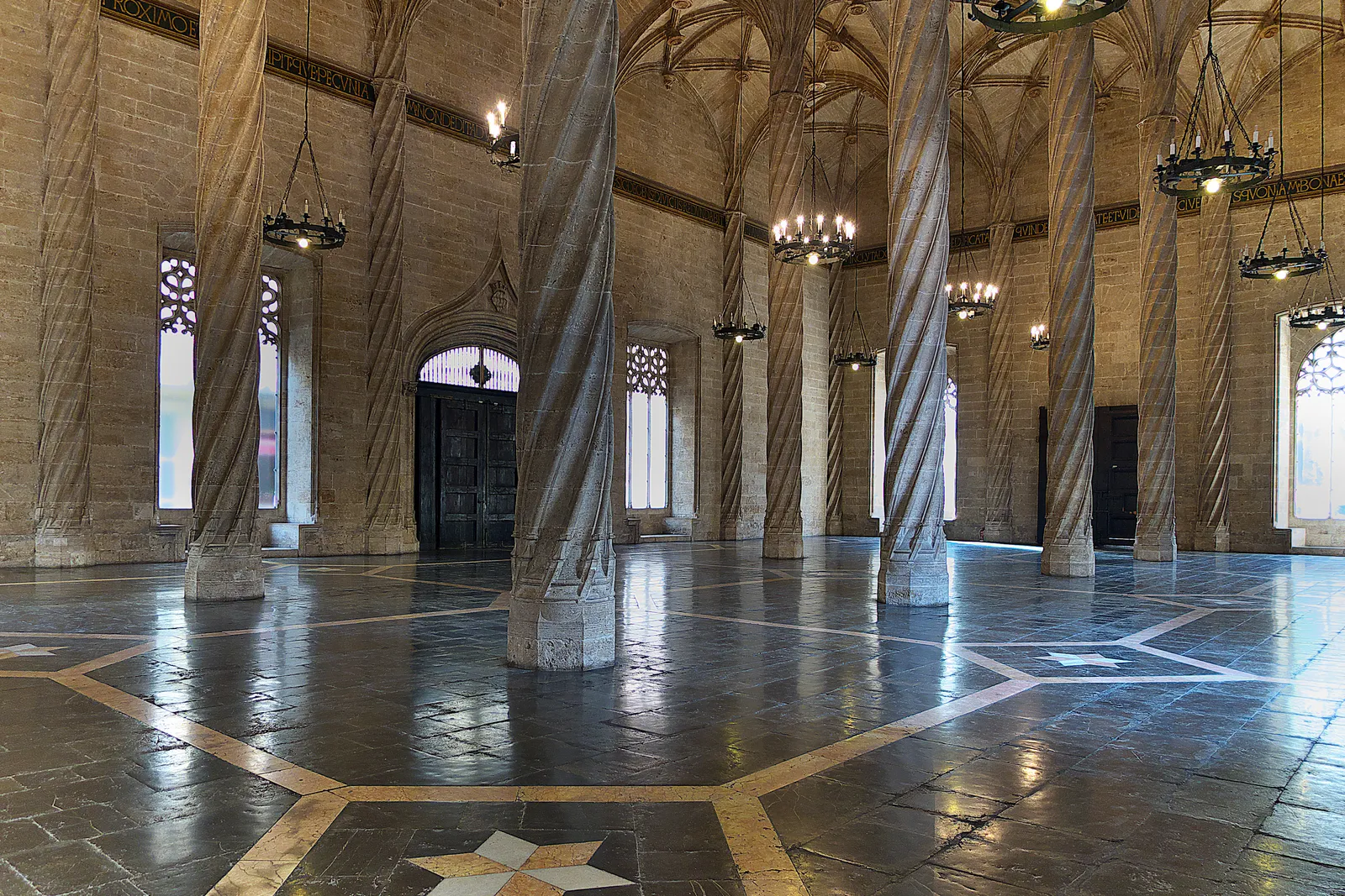 The trading hall of the Lonja de la Seda in Valencia, tall twisted stone columns rising from a patterned marble floor into the vault above