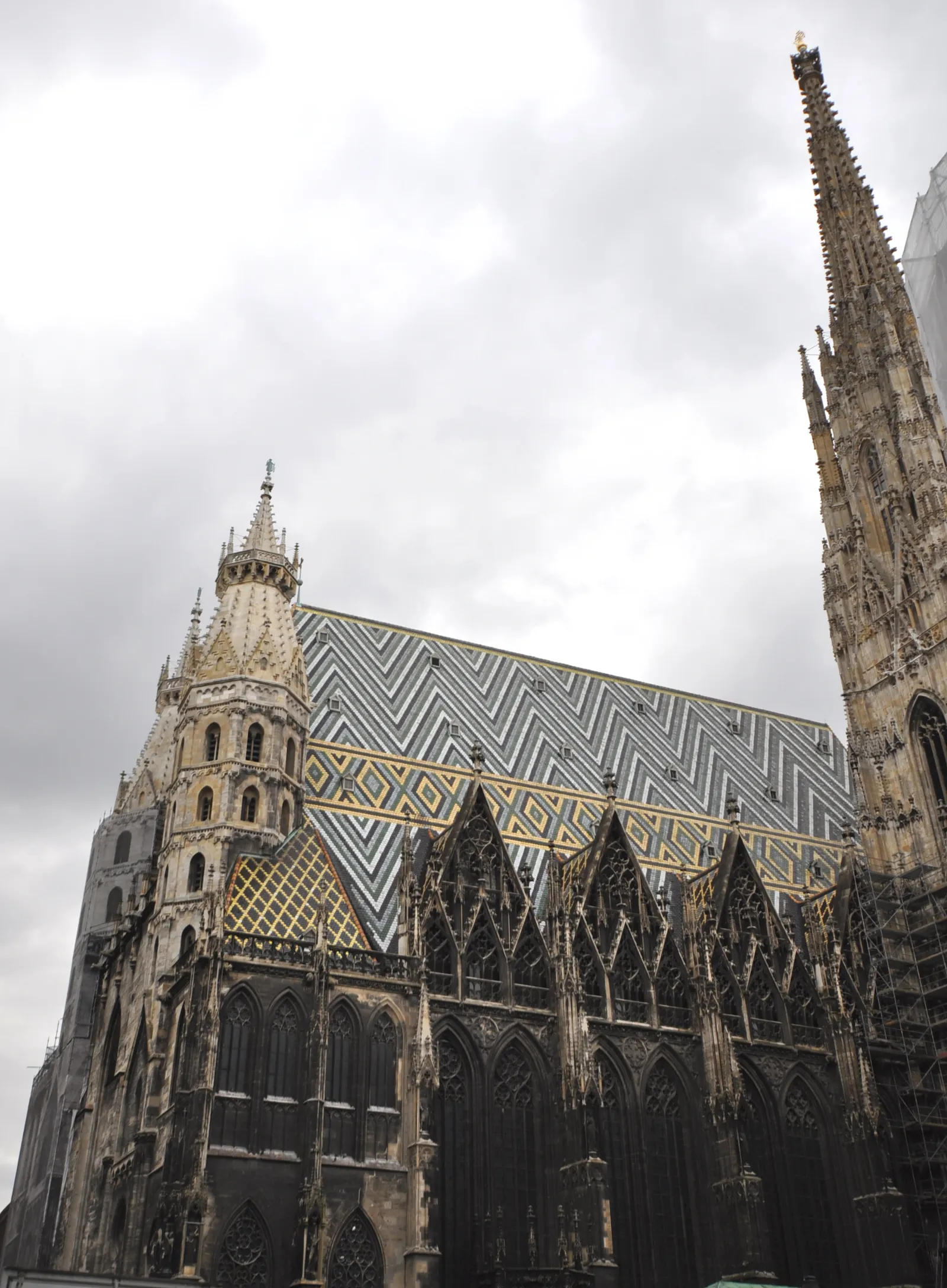 The south flank of St. Stephen's Cathedral in Vienna, showing the steep tiled roof laid in zigzag patterns of green, gold and black glazed tiles above the Gothic stonework