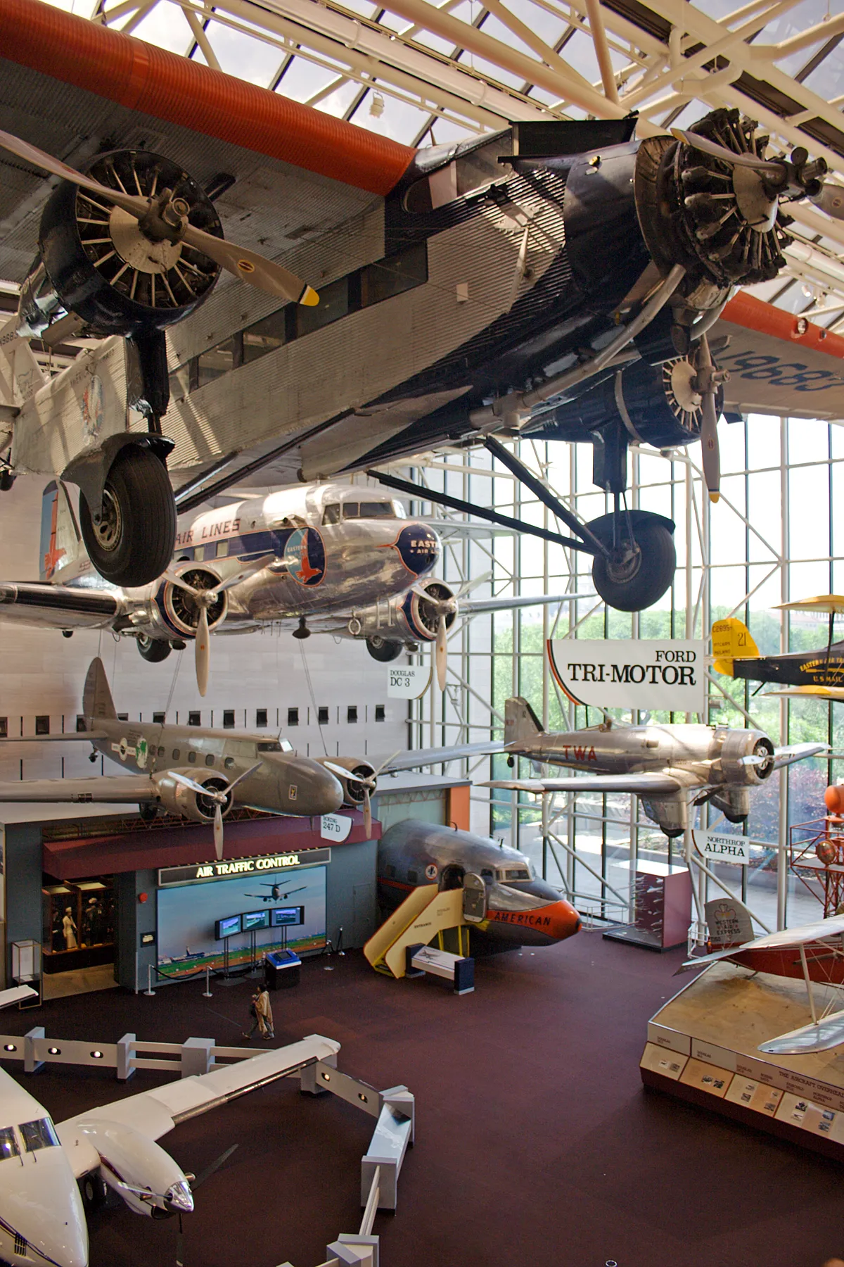 Historic airliners hanging from the ceiling of a hall at the National Air and Space Museum in Washington, including a Ford Tri-Motor and a Douglas DC-3 in Eastern Air Lines livery above the gallery floor