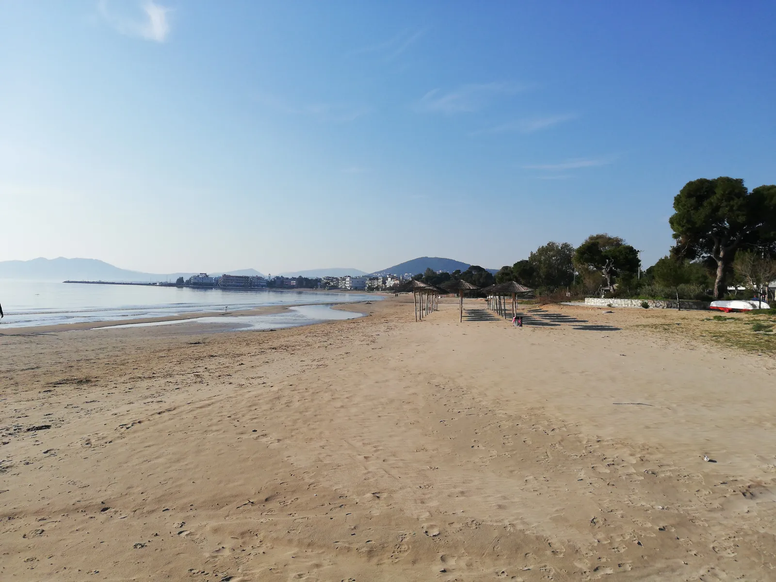 The wide sandy beach at Artemida on the east coast of Attica, with thatched umbrellas along the sand and hills across the bay
