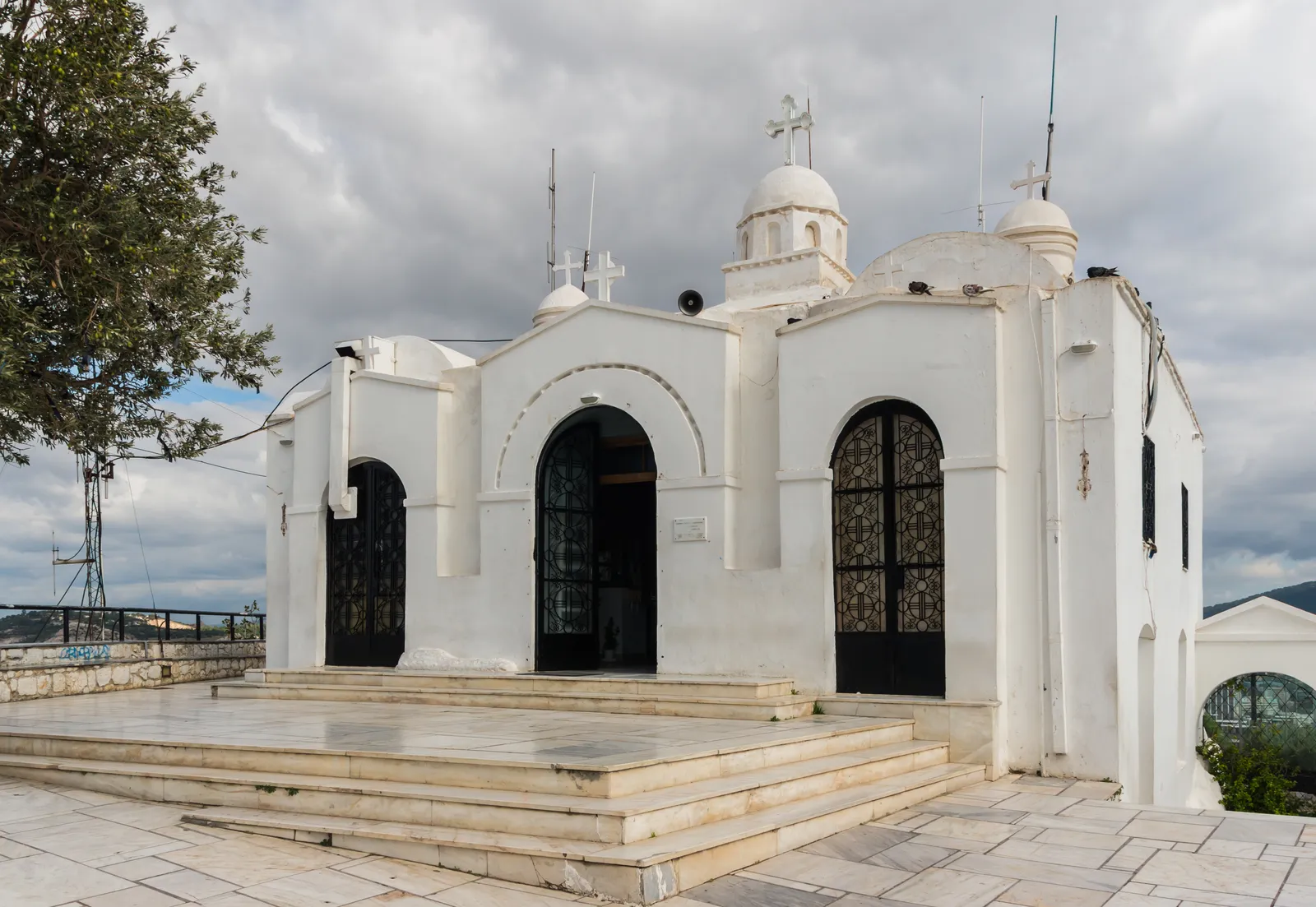 The small whitewashed chapel of Agios Georgios on the summit of Lycabettus in Athens, with three arched doorways and a bell cote