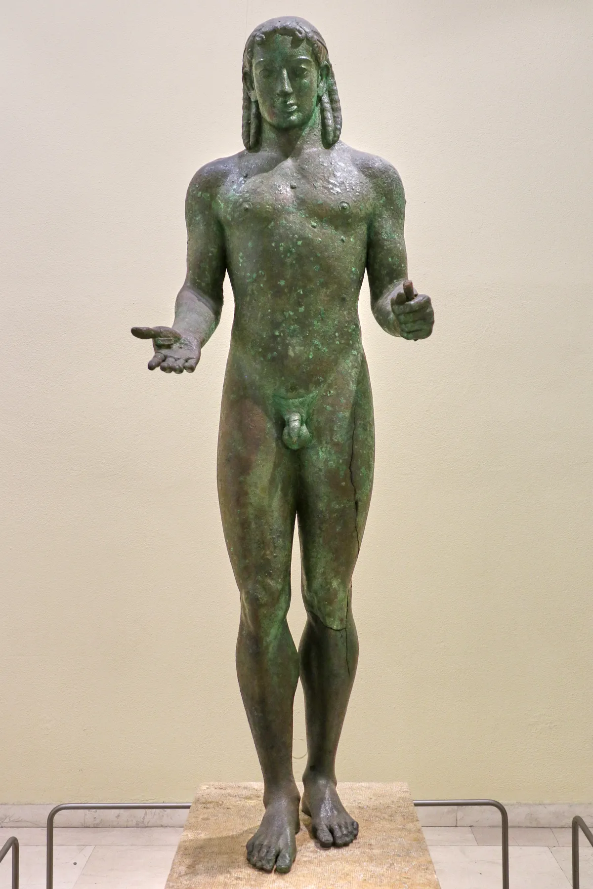 The life-size green bronze figure known as the Piraeus Apollo standing on a plinth in the Archaeological Museum of Piraeus
