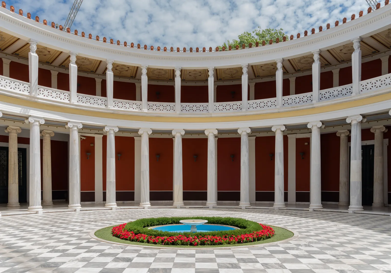 The circular colonnaded courtyard inside the Zappeion in Athens, with a chequerboard marble floor and a ring of red flowers around a small fountain