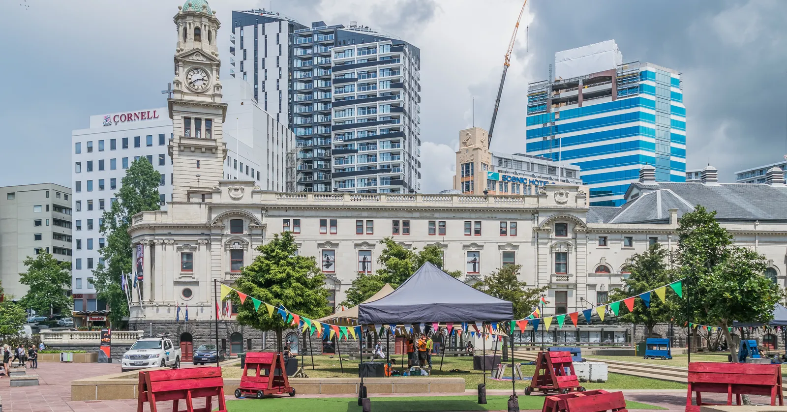 Aotea Square in Auckland with the Edwardian stone facade and clock tower of Auckland Town Hall along one side, bunting strung over the paving and apartment towers behind