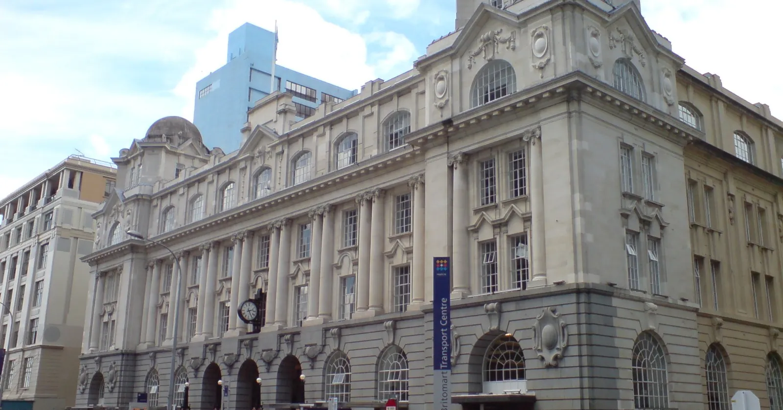 The Edwardian stone facade of Auckland's former Chief Post Office on Queen Street, now the entrance to Waitematā Station, with a clock mounted above the arched ground-floor windows