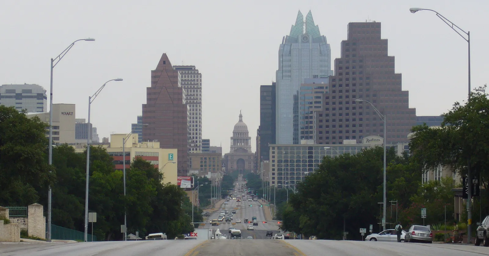 The view north up South Congress Avenue in Austin, the road running dead straight between trees and low buildings toward the Capitol dome framed by downtown towers on either side