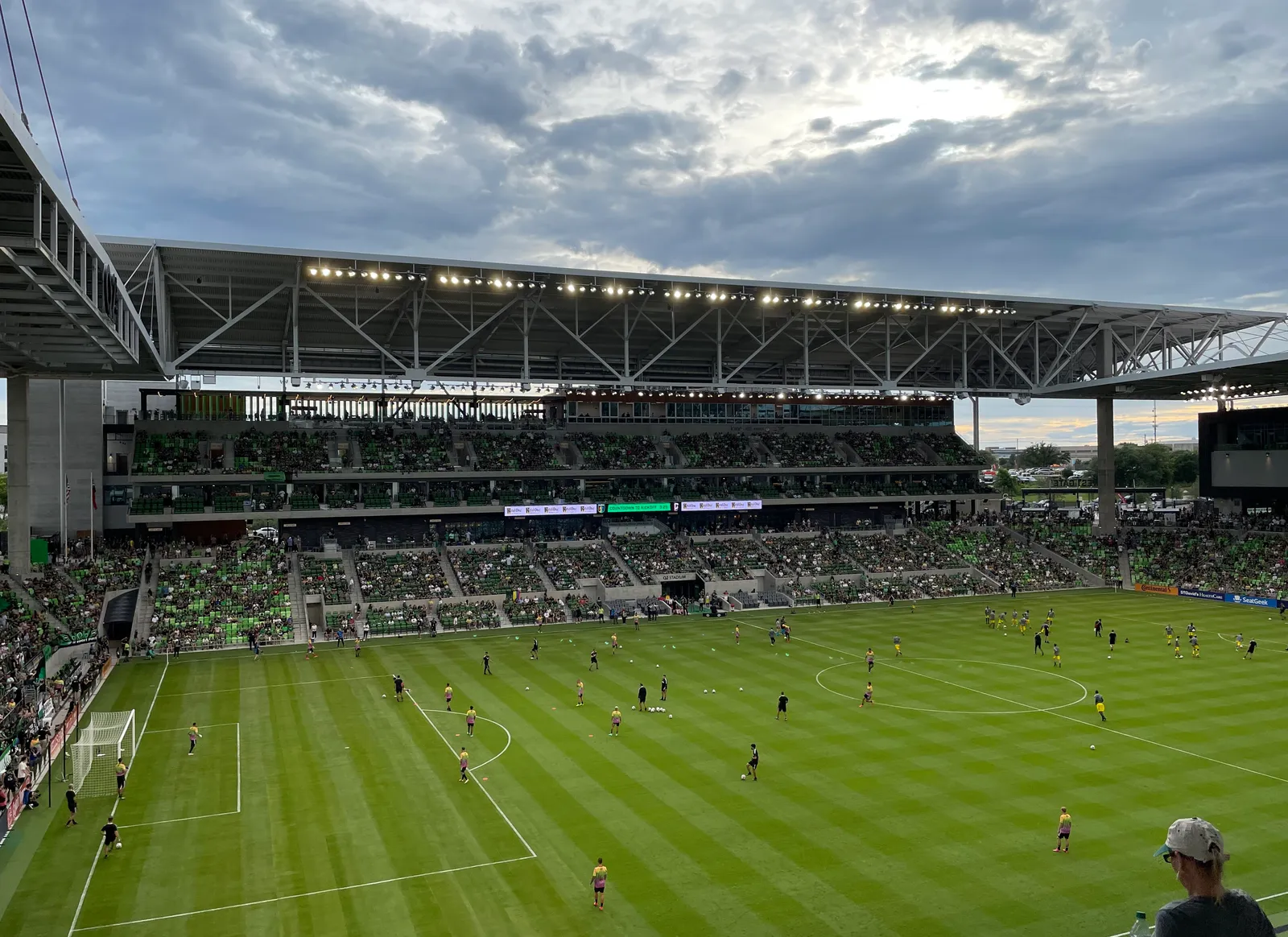 Q2 Stadium in Austin during a match, the green pitch below a packed single-tier bowl with a cantilevered roof over the far stand and a crowd in green behind the goal