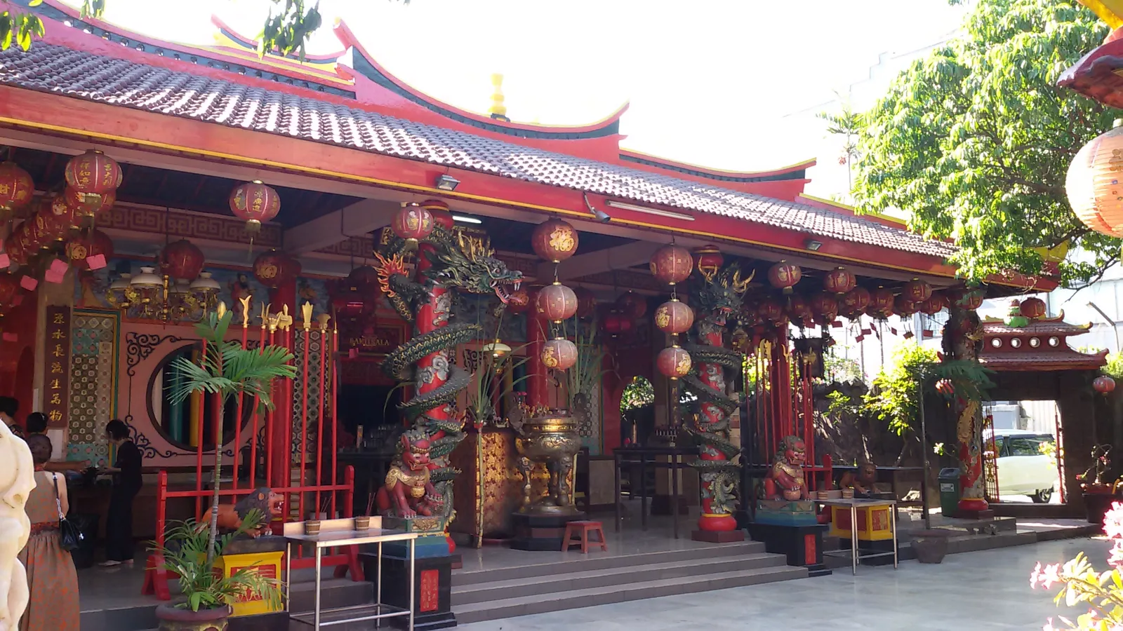 The red and gold front of Vihara Dharmayana in Kuta, a Chinese Buddhist temple hung with red lanterns, its roof edge tiled and its columns wound with painted dragons