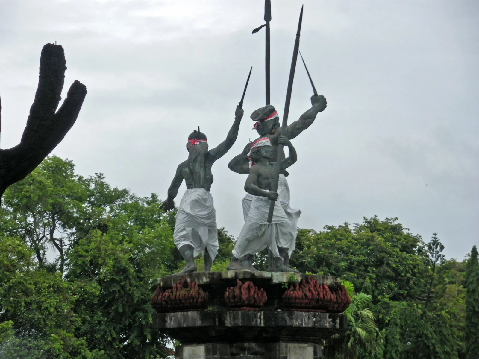 The stone memorial group on Puputan Badung Square in Denpasar, three figures in Balinese dress raising a spear and a kris above a plinth carved with flames
