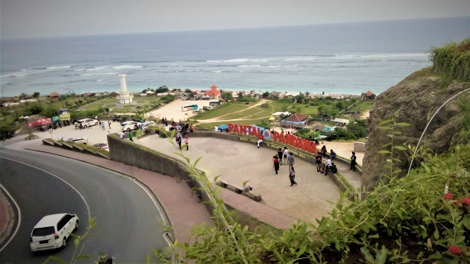 The road cut down through the limestone to Pantai Pandawa in Bali, with the beach's name spelled in large coloured letters on the terrace above the white sand