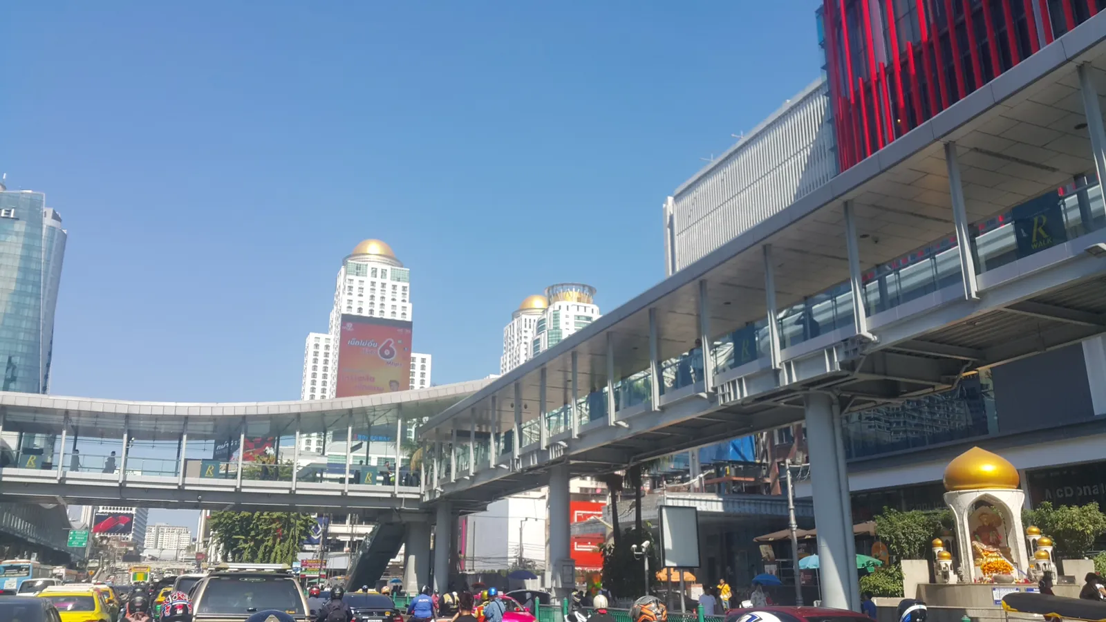 The Ratchaprasong skywalk in Bangkok, a covered elevated footbridge on concrete piers running above six lanes of traffic and linking into the upper floors of the buildings on both sides