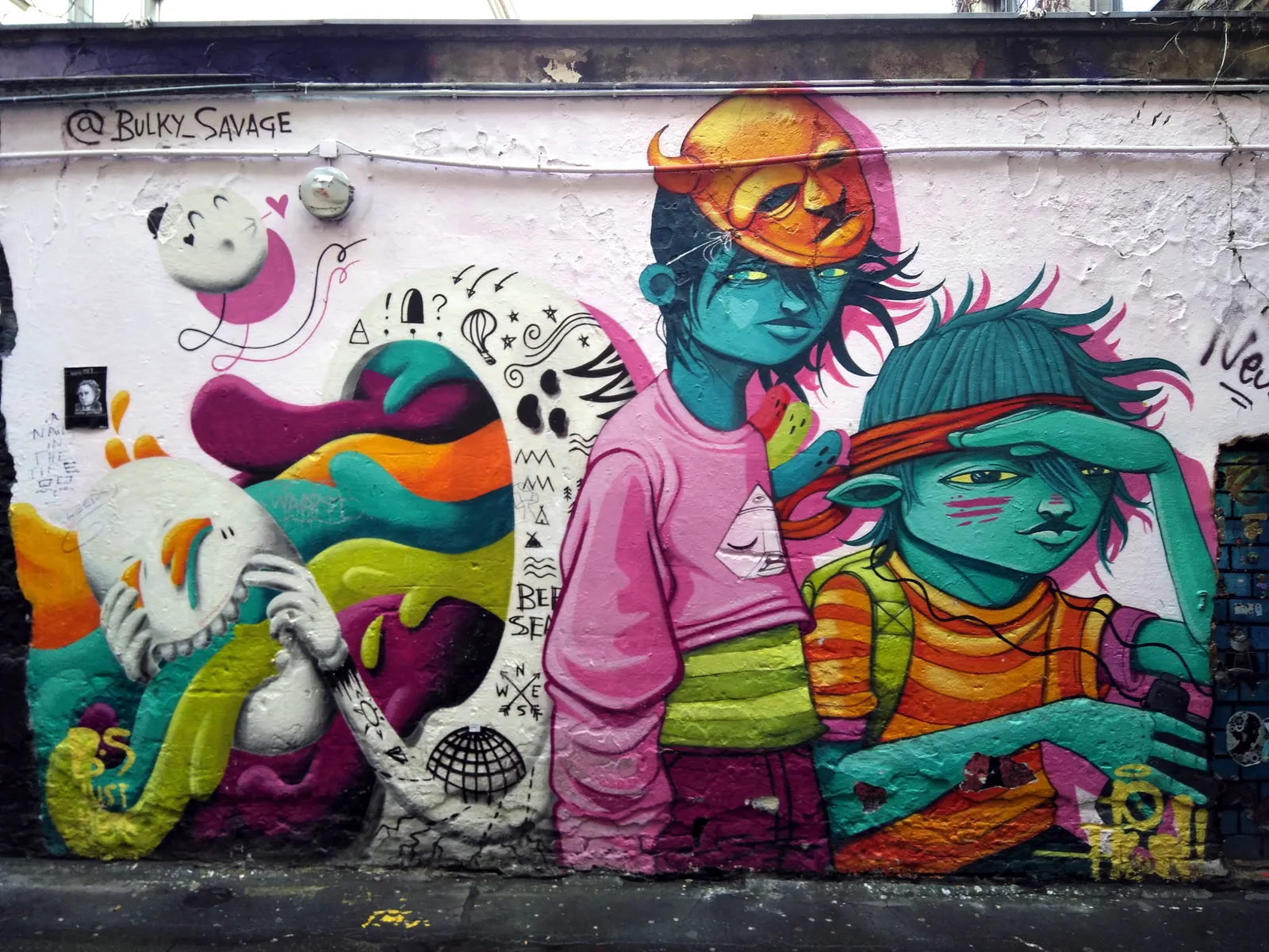 A large colourful mural of stylised figures covering a battered wall in the courtyard of Haus Schwarzenberg in Berlin, surrounded by stickers and tags on the bare plaster