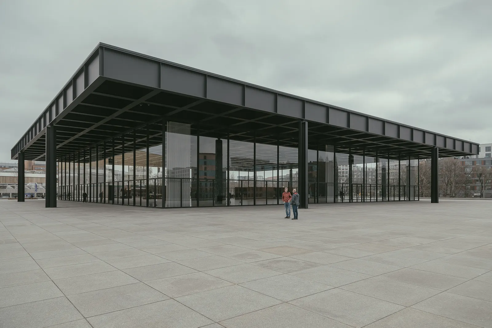 The Neue Nationalgalerie in Berlin, Mies van der Rohe's flat black steel roof carried on eight columns above a fully glazed hall, standing on an empty granite terrace