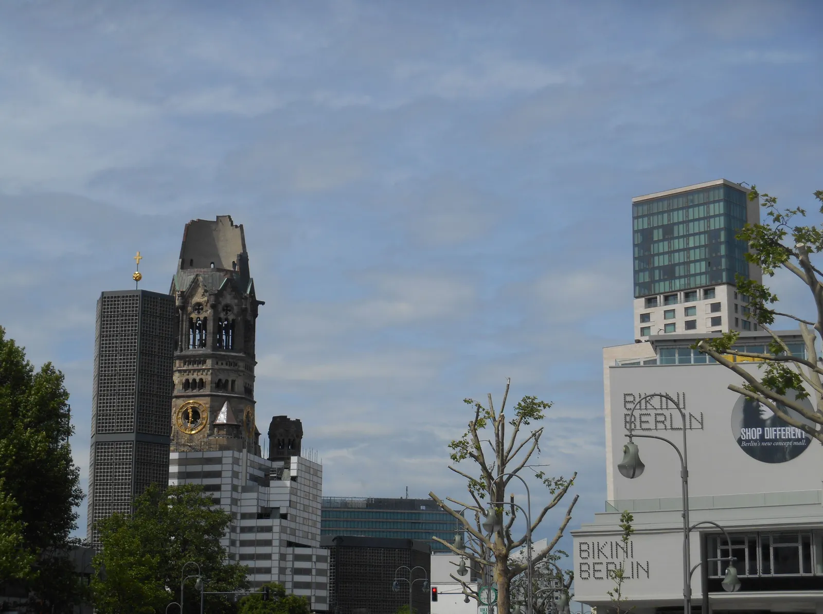 The broken tower of the Kaiser Wilhelm Memorial Church on the left and the white Bikini Berlin building with its rooftop storey on the right, seen across Budapester Straße