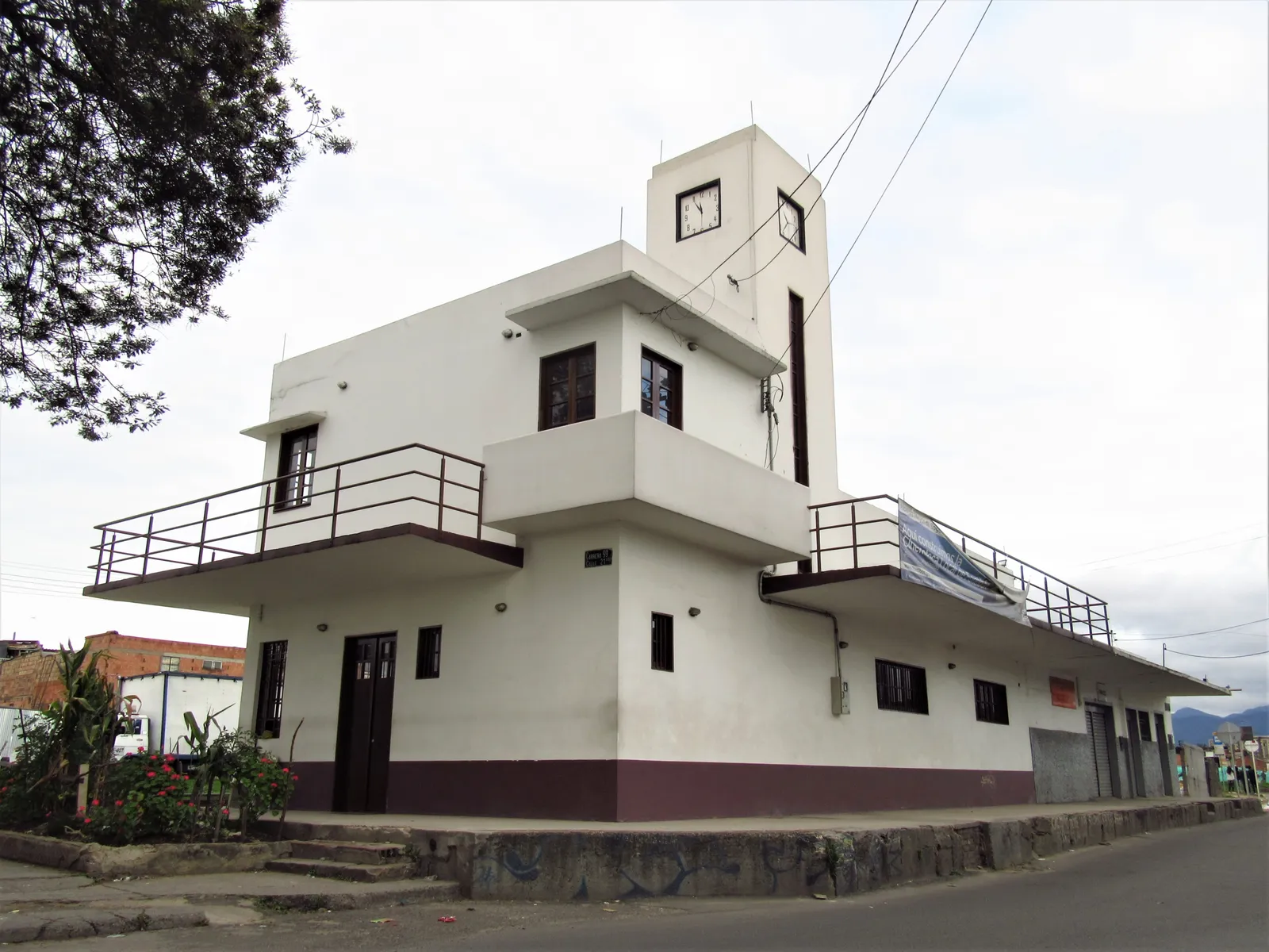 The old railway station at Fontibón in Bogotá, a white two-storey building with a square tower, balcony rails and a raised platform along the street side
