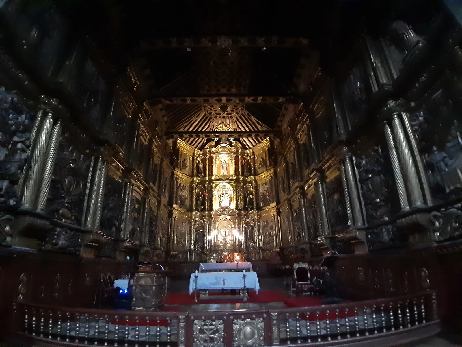 The gilded wooden altarpiece filling the presbytery of the San Francisco church in Bogotá, rising in carved tiers around a central figure above the altar in a dim interior