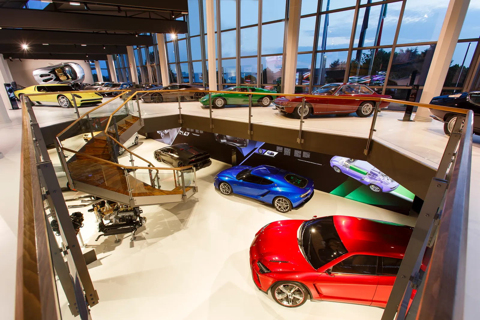 Inside the Lamborghini Museum in Sant'Agata Bolognese, sports cars in red, blue, green and yellow displayed on two levels of a glass-walled hall