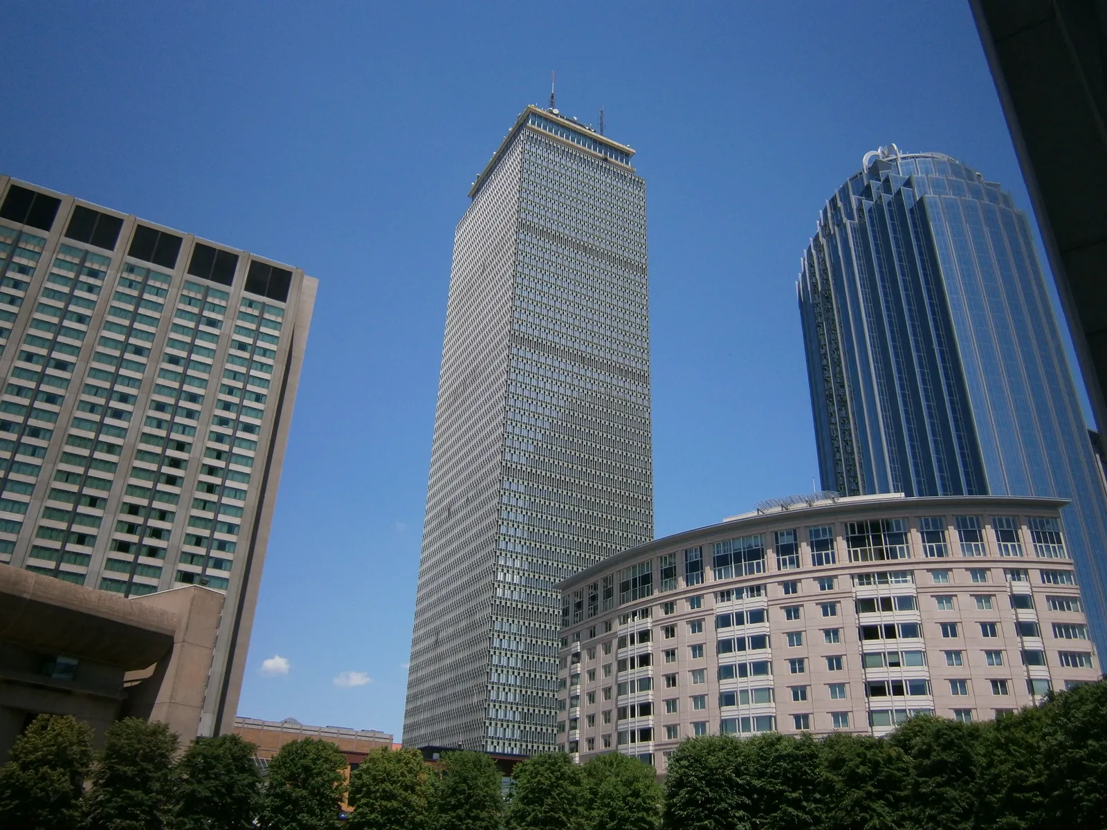 The Prudential Tower in Boston seen from street level, a flat-topped grey office slab standing well above the lower blocks and a glass tower beside it
