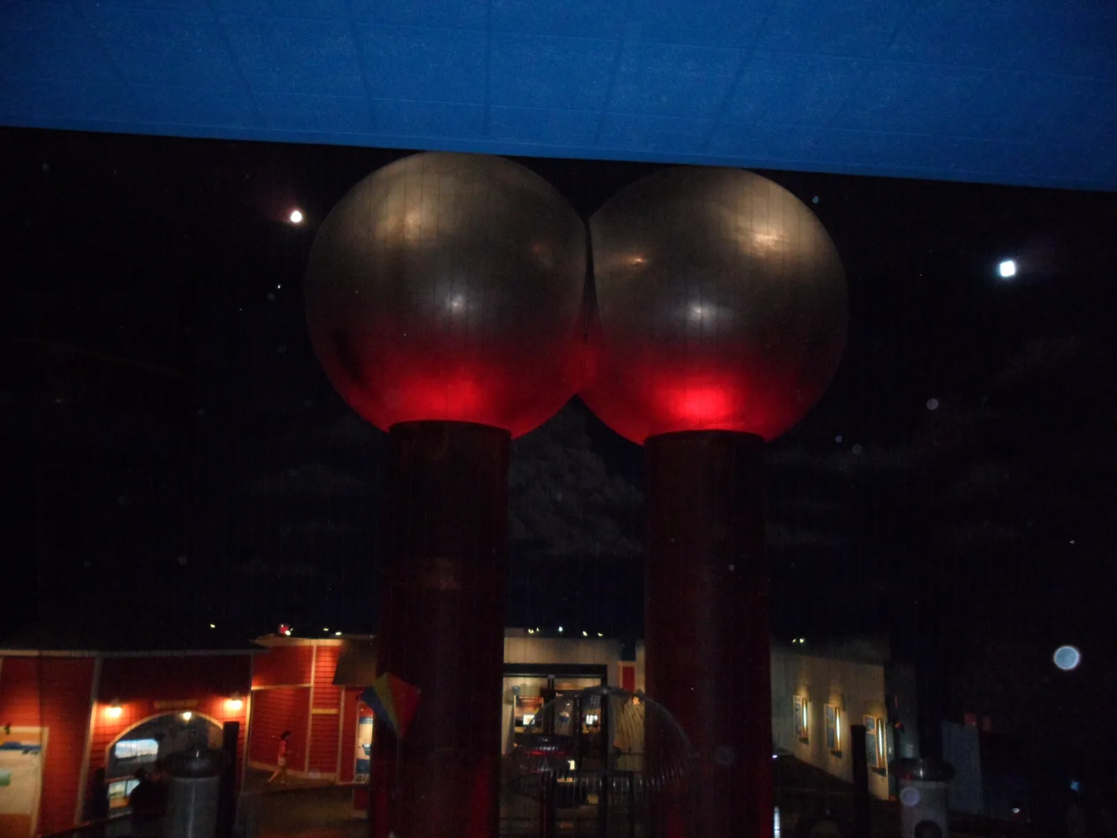 Two polished aluminium spheres on tall red columns standing in the darkened Theater of Electricity at the Museum of Science in Boston, lit red from below