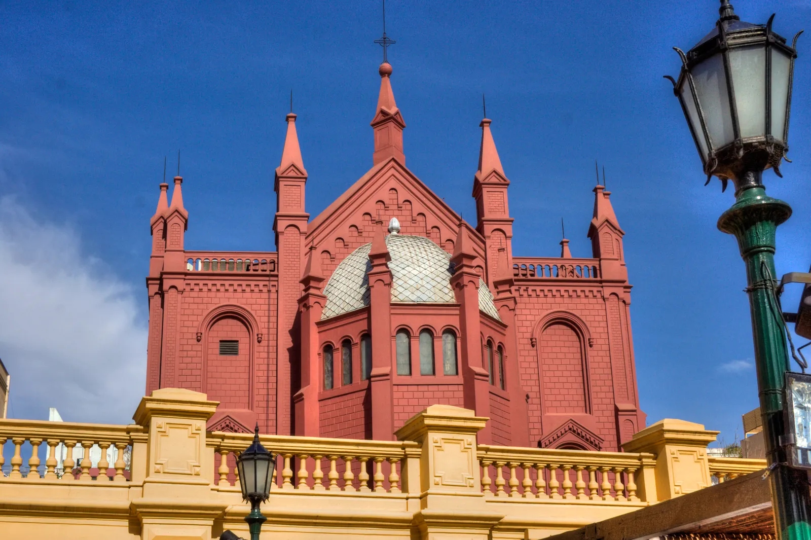 The red brick gable and pinnacles of the Centro Cultural Recoleta in Buenos Aires rising above a yellow balustrade, with a tiled half-dome over the central window against a blue sky