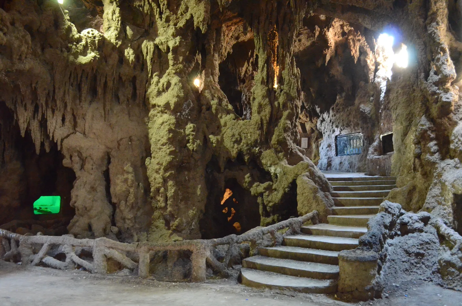 Inside the Aquarium Grotto Garden in Zamalek, a passage of artificial rock formed into stalactites and hollows with a flight of stone steps rising through it and a rustic railing along the path