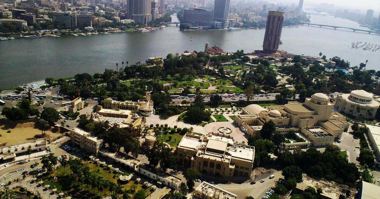 Gezira island seen from high up, the opera house complex and its gardens filling the foreground, the Nile curving past on the left and the towers of central Cairo across the water