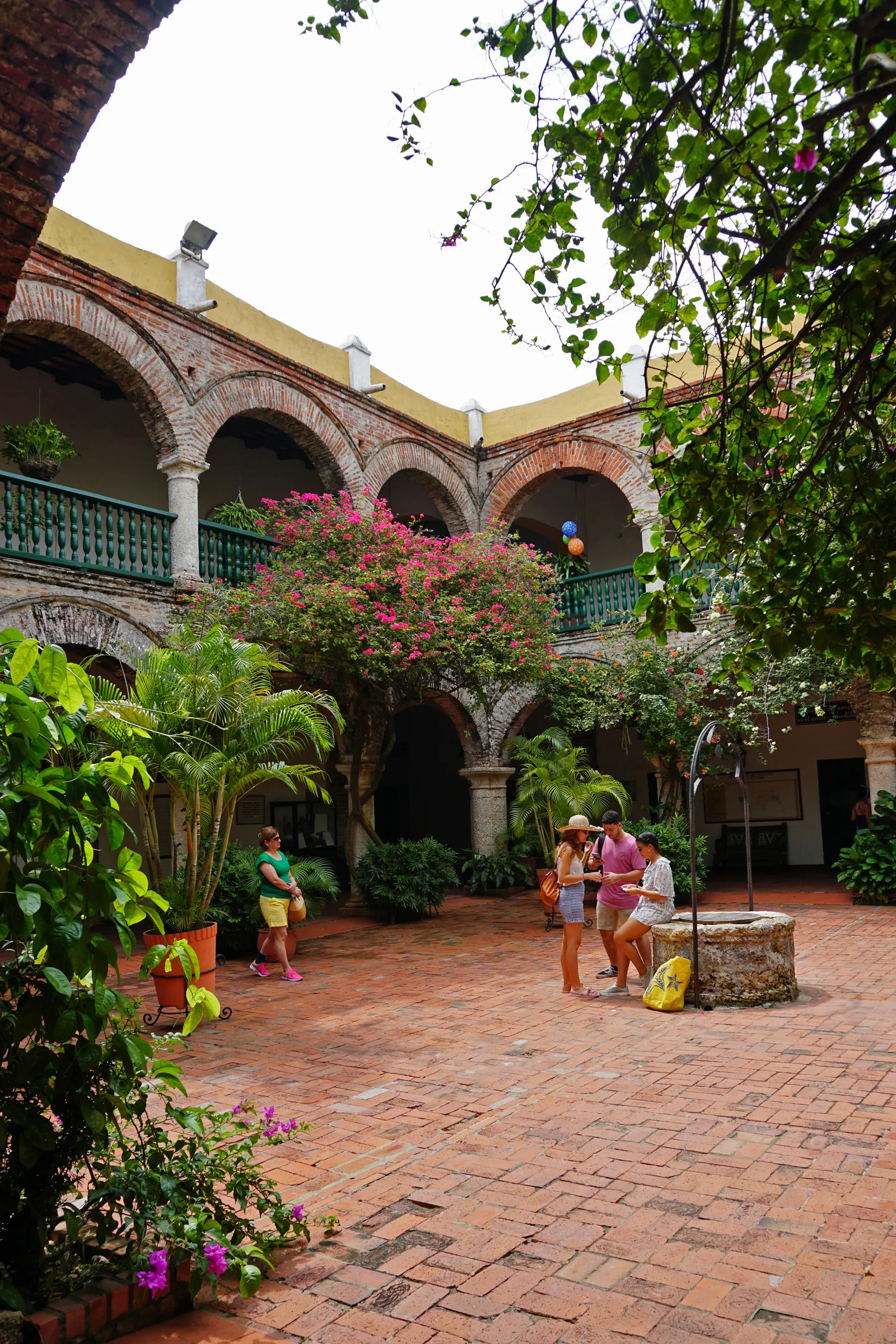 The colonial courtyard of Convento de la Popa in Cartagena, with whitewashed arches, a well, and bougainvillea in bloom