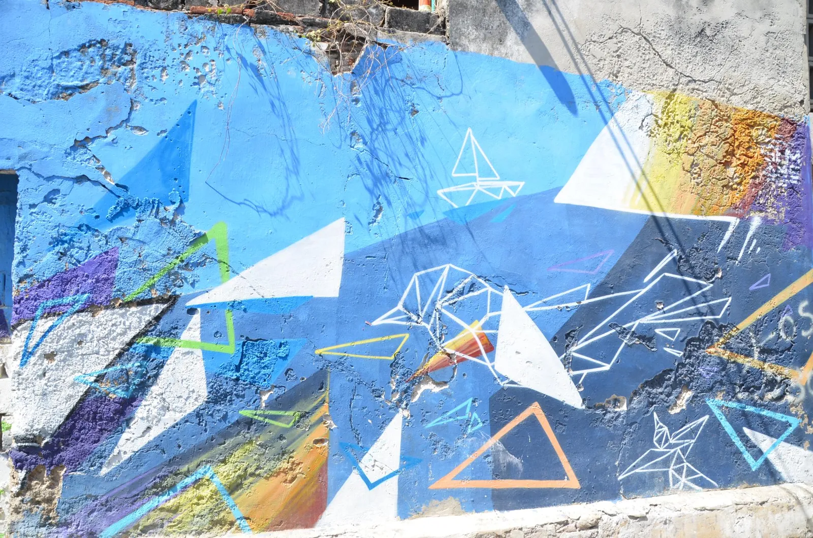 An abstract geometric mural in blue, white and orange painted across a weathered wall in Getsemani, Cartagena