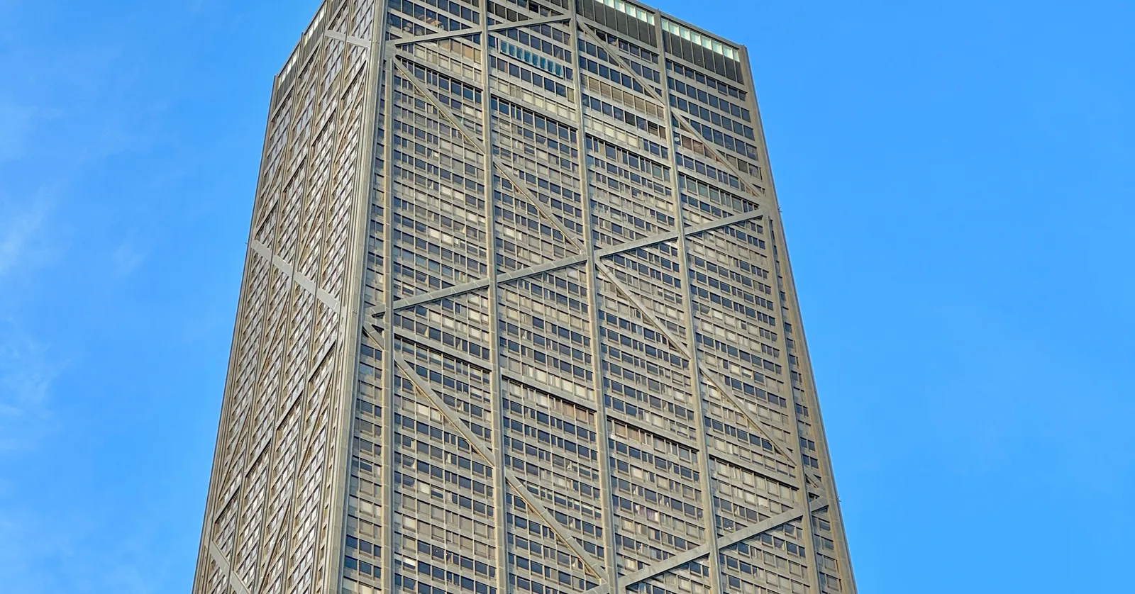 The tapering black tower at 875 North Michigan Avenue in Chicago seen from the street below, its facade crossed by the giant white X-braces that run up the outside of the building