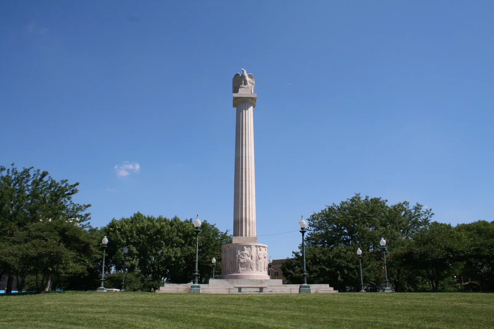 The Illinois Centennial Monument in Chicago's Logan Square, a tall white Doric column topped by an eagle, standing over a lawn under a clear blue sky
