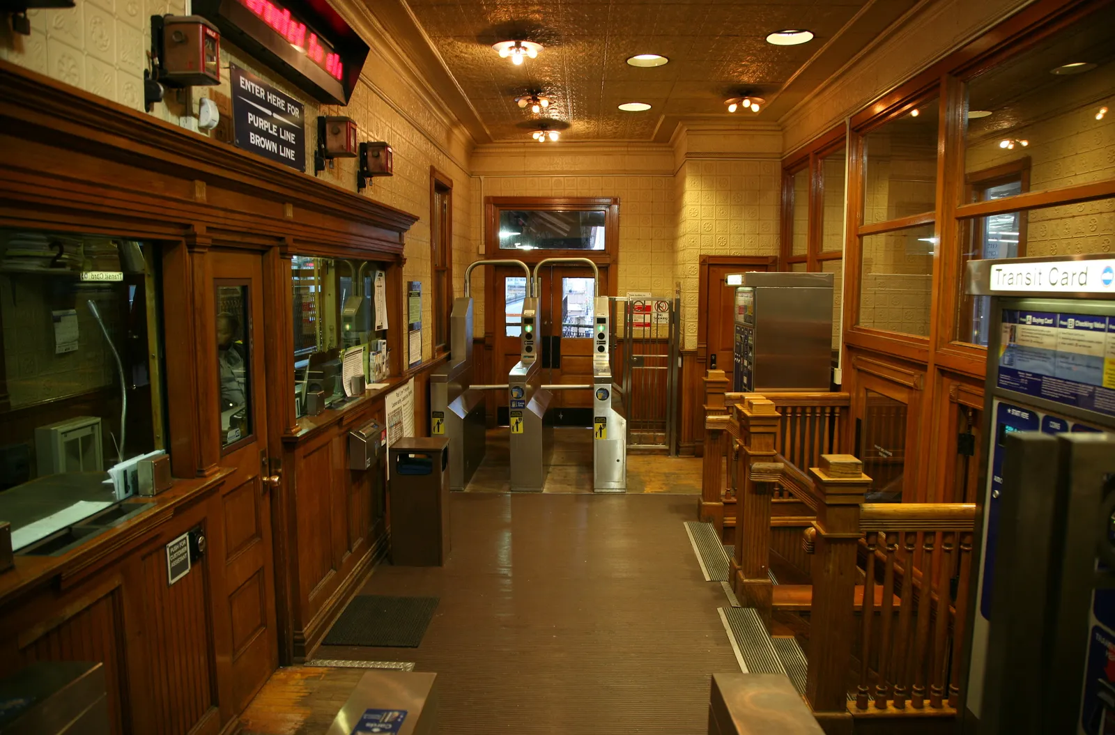 The wood-paneled station house at Quincy on Chicago's elevated Loop, with an old ticket booth on the left, a pressed-metal ceiling and turnstiles leading to the platforms