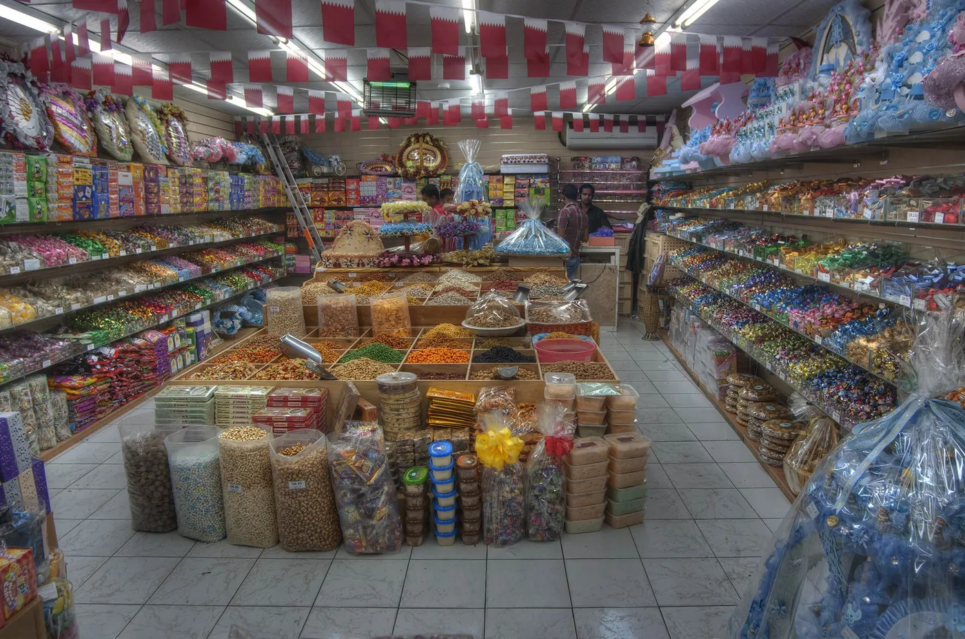 Inside a shop at Souq Waqif in Doha, open sacks and jars of nuts, dried fruit and spices stacked in the middle of the floor with shelves of packets on both sides