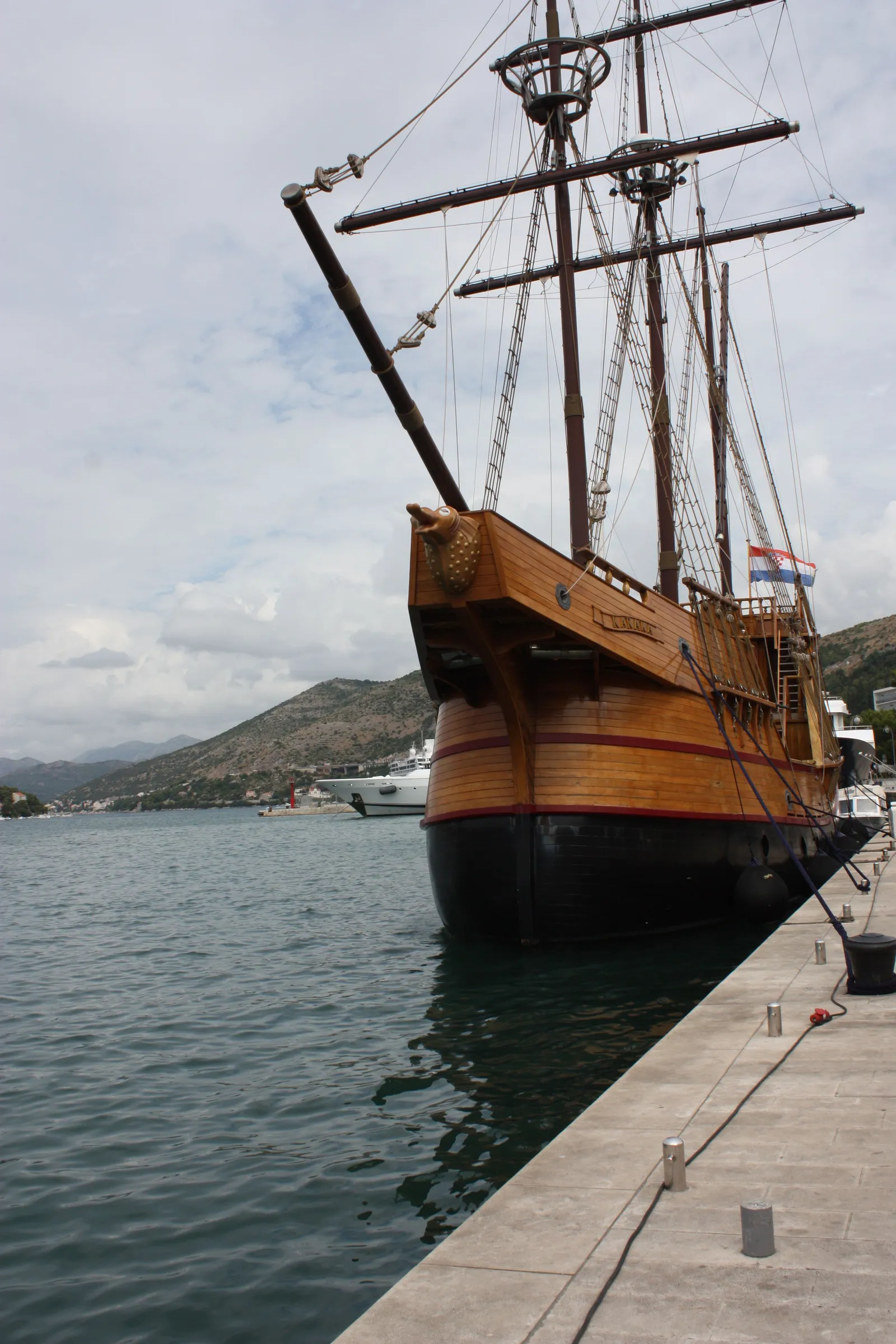 The Karaka, a wooden replica of a 16th-century Dubrovnik merchant ship, moored bow-on at the Gruž quay with three masts, a carved stern and a Croatian flag at the rail