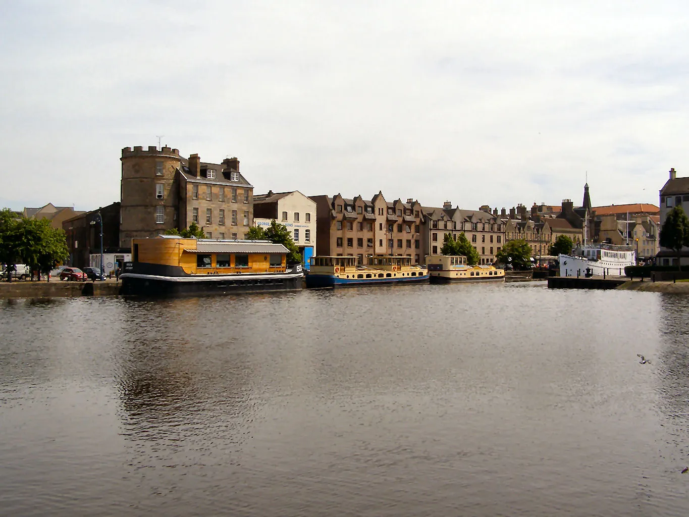 Houseboats and historic buildings along The Shore in Leith, Edinburgh, with the Water of Leith in the foreground