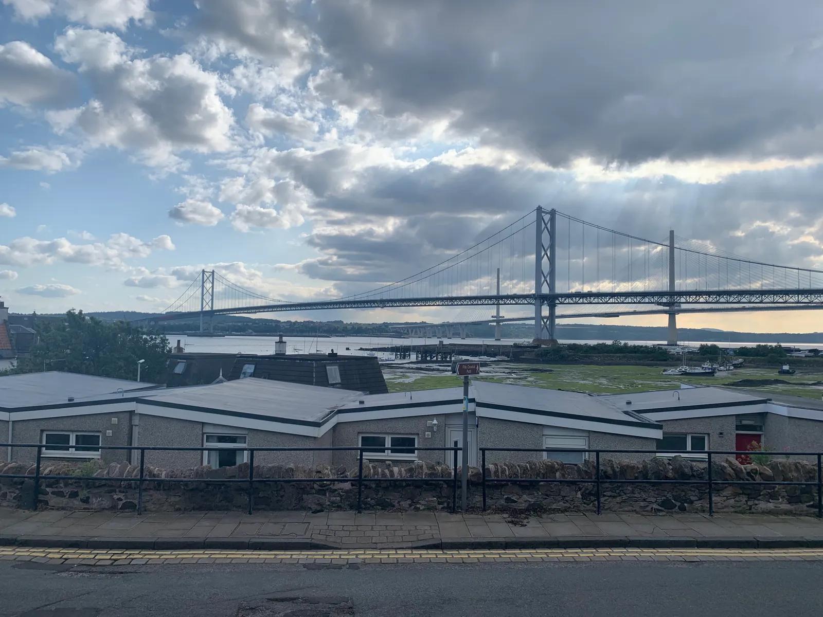 The Forth Road Bridge's suspension towers seen from the South Queensferry shore, with the taller cable-stayed pylons of the Queensferry Crossing behind them