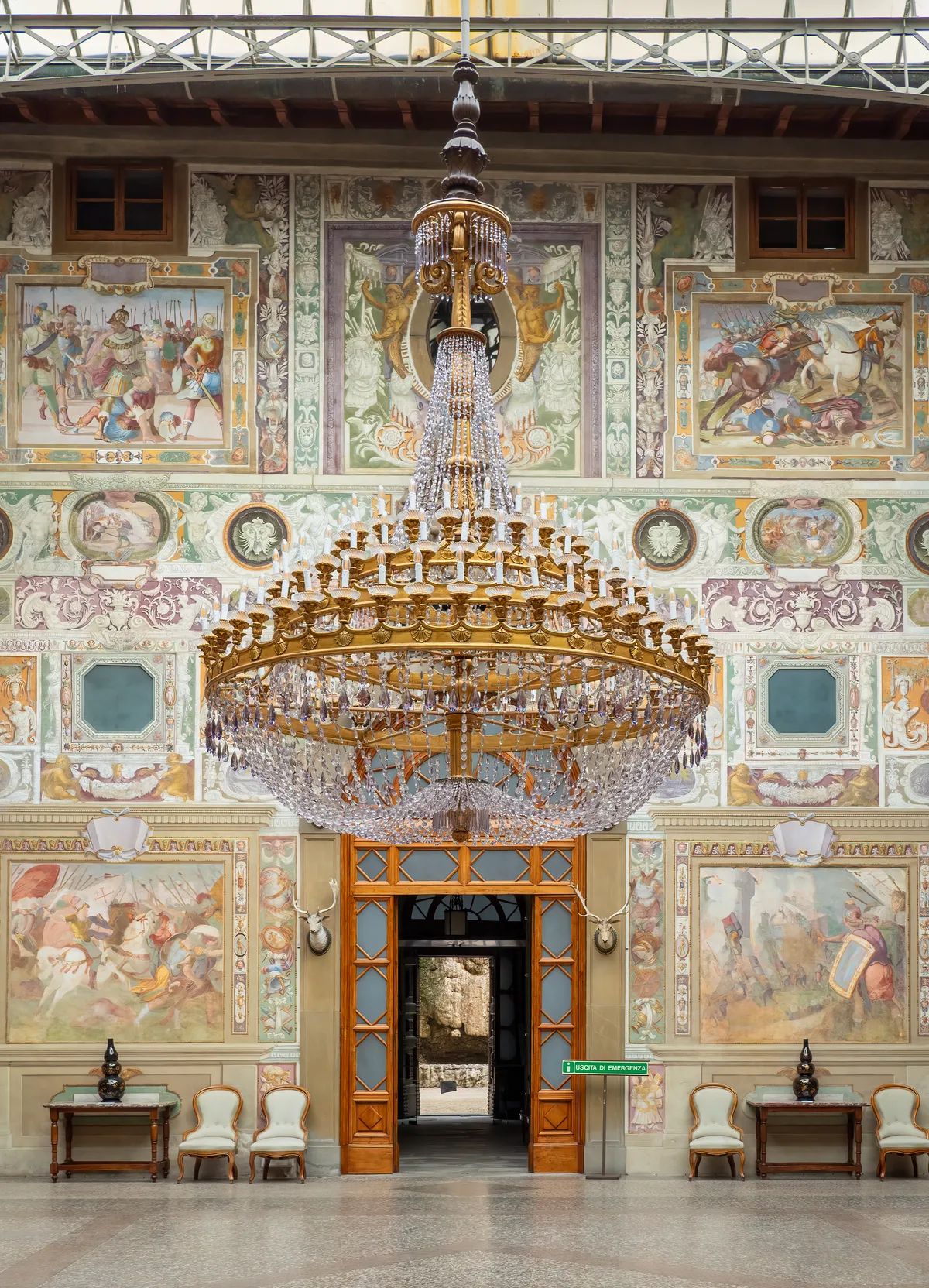 The frescoed courtyard of Villa La Petraia near Florence, roofed over in glass, with a crystal chandelier hanging in front of painted walls