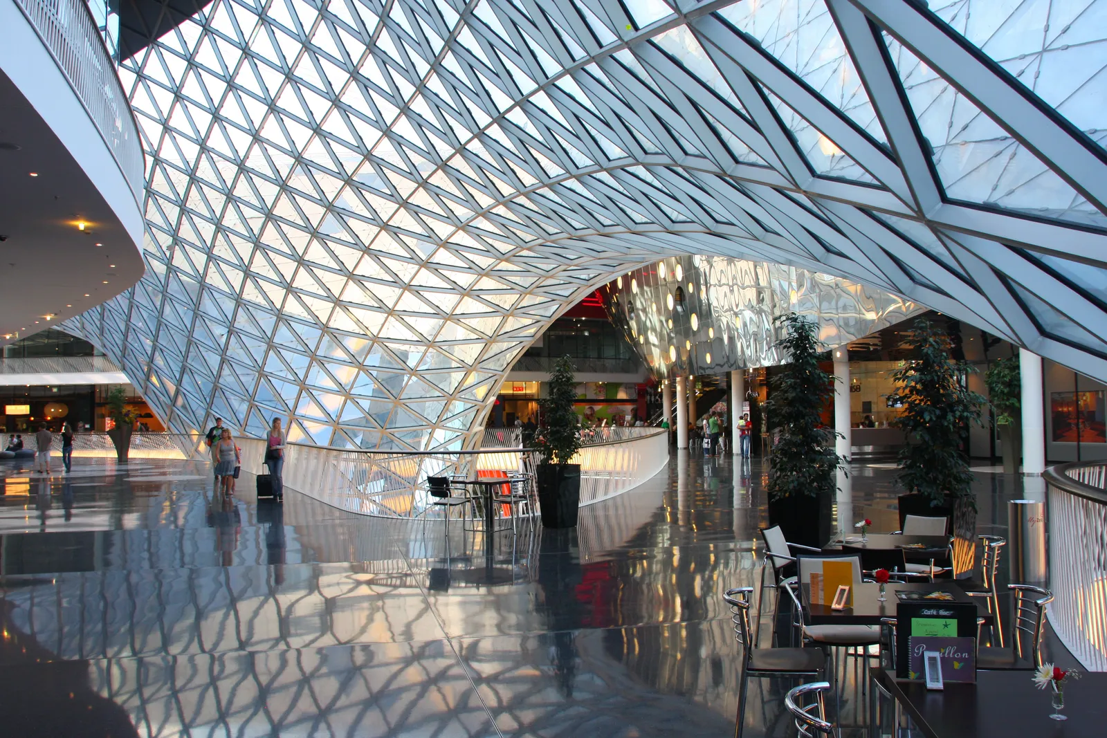 The inside of MyZeil's funnel-shaped glass atrium in Frankfurt, a swirling white lattice structure spiralling up through several shopping floors
