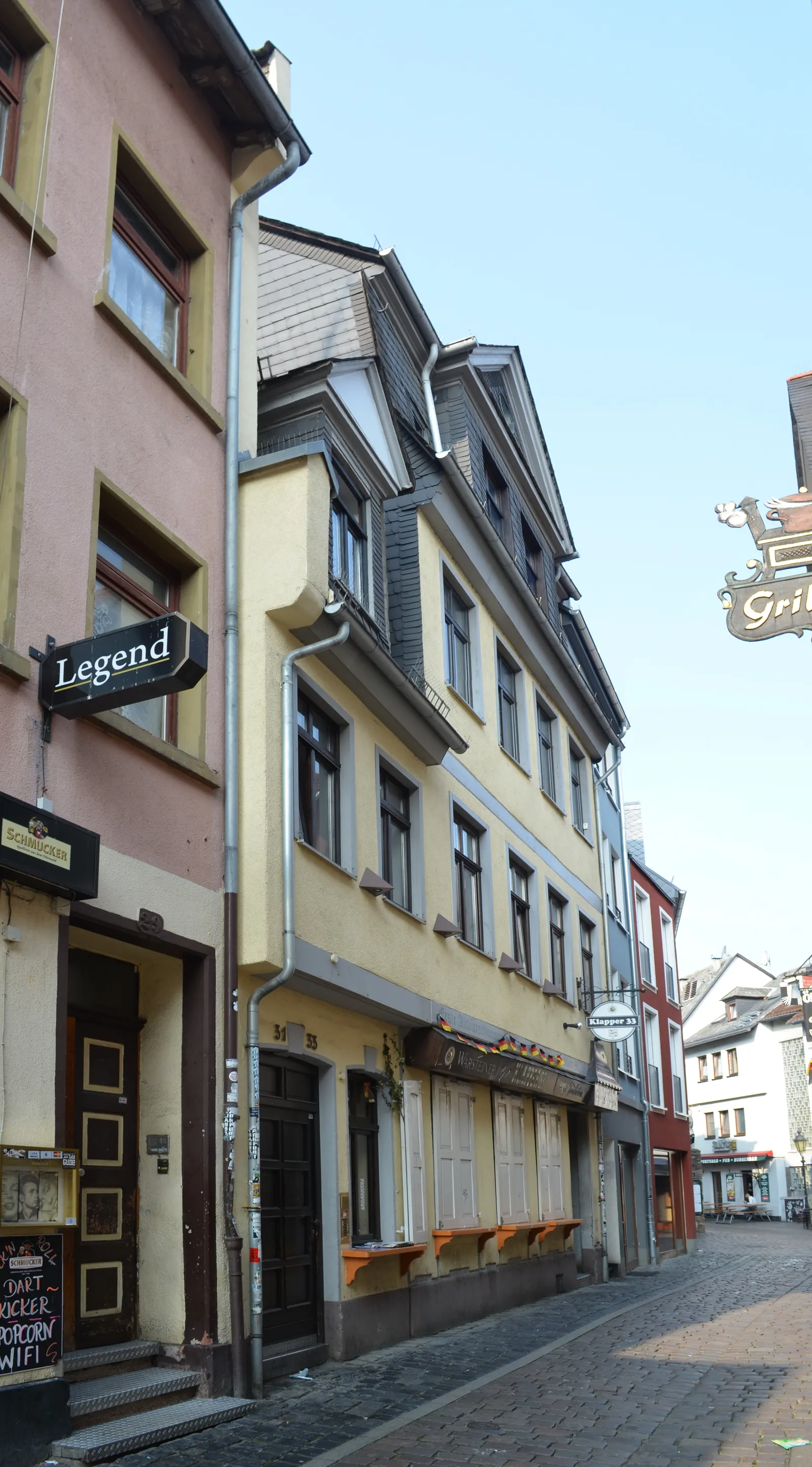 A narrow cobbled street in Alt-Sachsenhausen lined with pastel-colored timber-framed buildings and illuminated bar signs