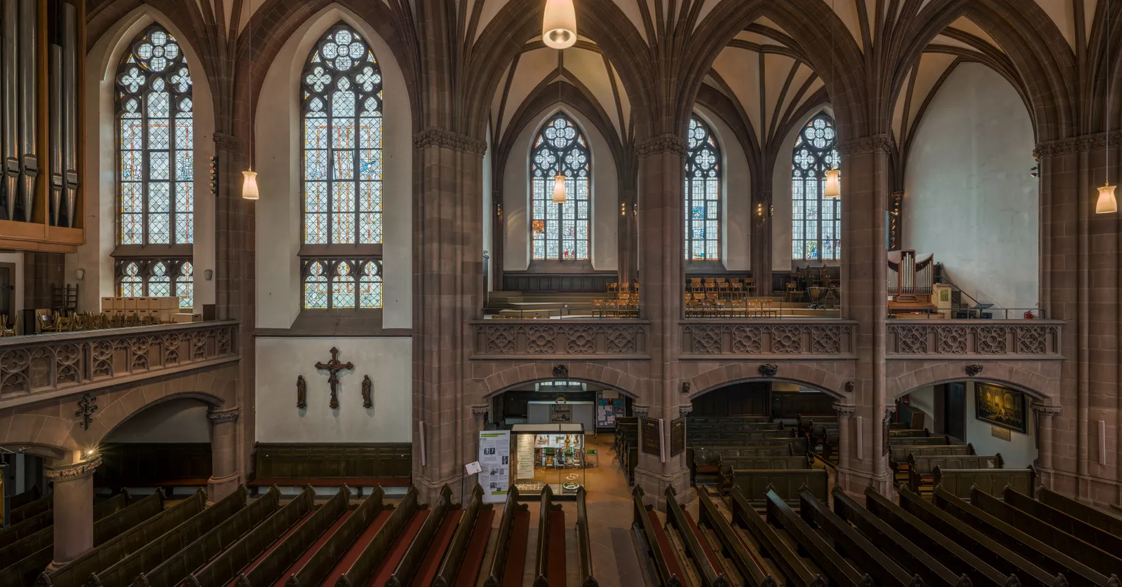 The vaulted Gothic revival nave of Dreikönigskirche in Frankfurt, tall stained-glass windows lit from outside above rows of wooden pews