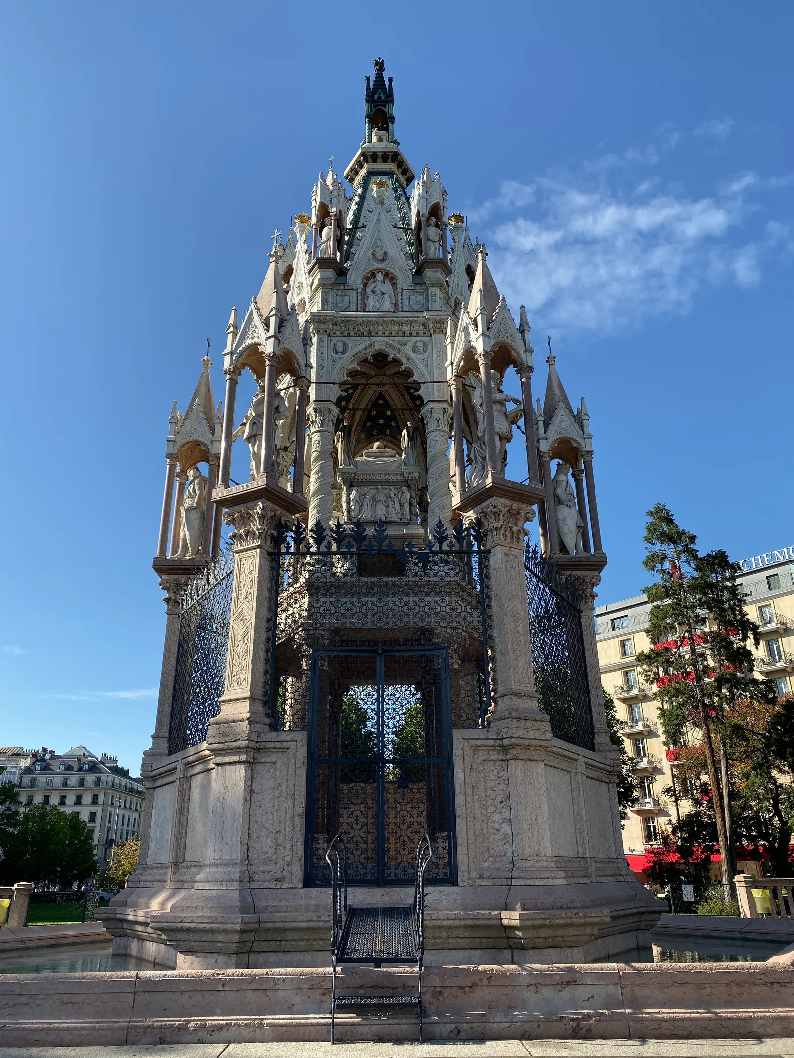The Brunswick Monument in Geneva, a tall white marble canopy of Gothic pinnacles and arches raised on a stepped stone platform beside the lake
