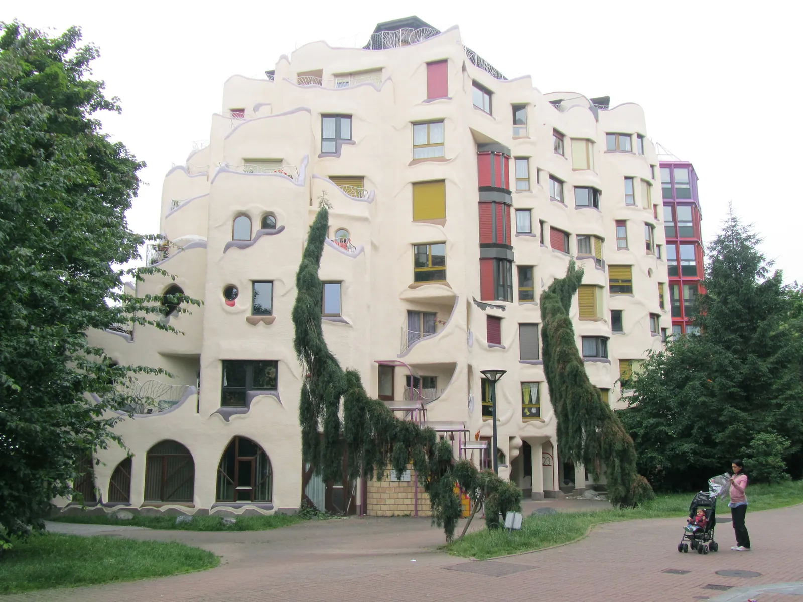 One of the Schtroumpfs buildings in Geneva's Grottes quarter, a pale curving apartment block with irregular windows, rounded balconies and red and yellow window frames