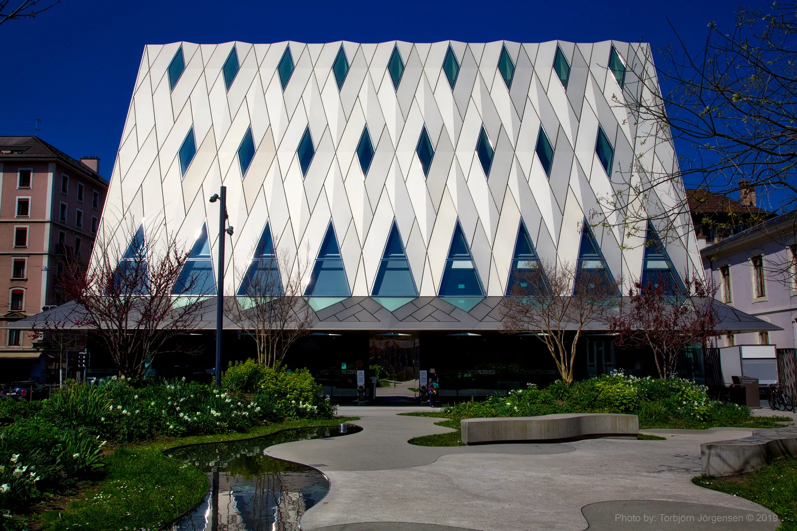 The ethnography museum in Geneva, a low white building whose facade folds into a grid of diamond panels with dark green glazing set between them