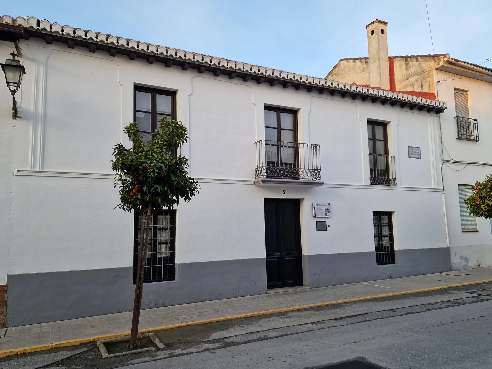 The whitewashed two-storey house in Fuente Vaqueros where Federico García Lorca was born, now a museum, with wooden shutters, a small iron balcony and an orange tree on the pavement outside
