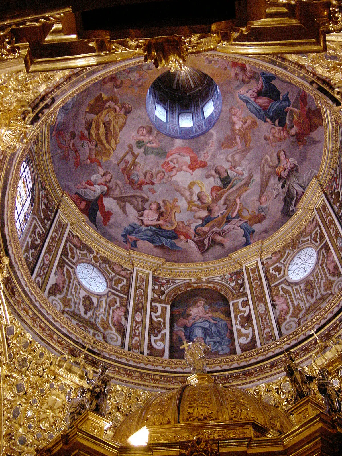 The painted dome inside the Basílica de San Juan de Dios in Granada, frescoed angels and saints ringed by gilded Baroque carving above the gold top of the altarpiece