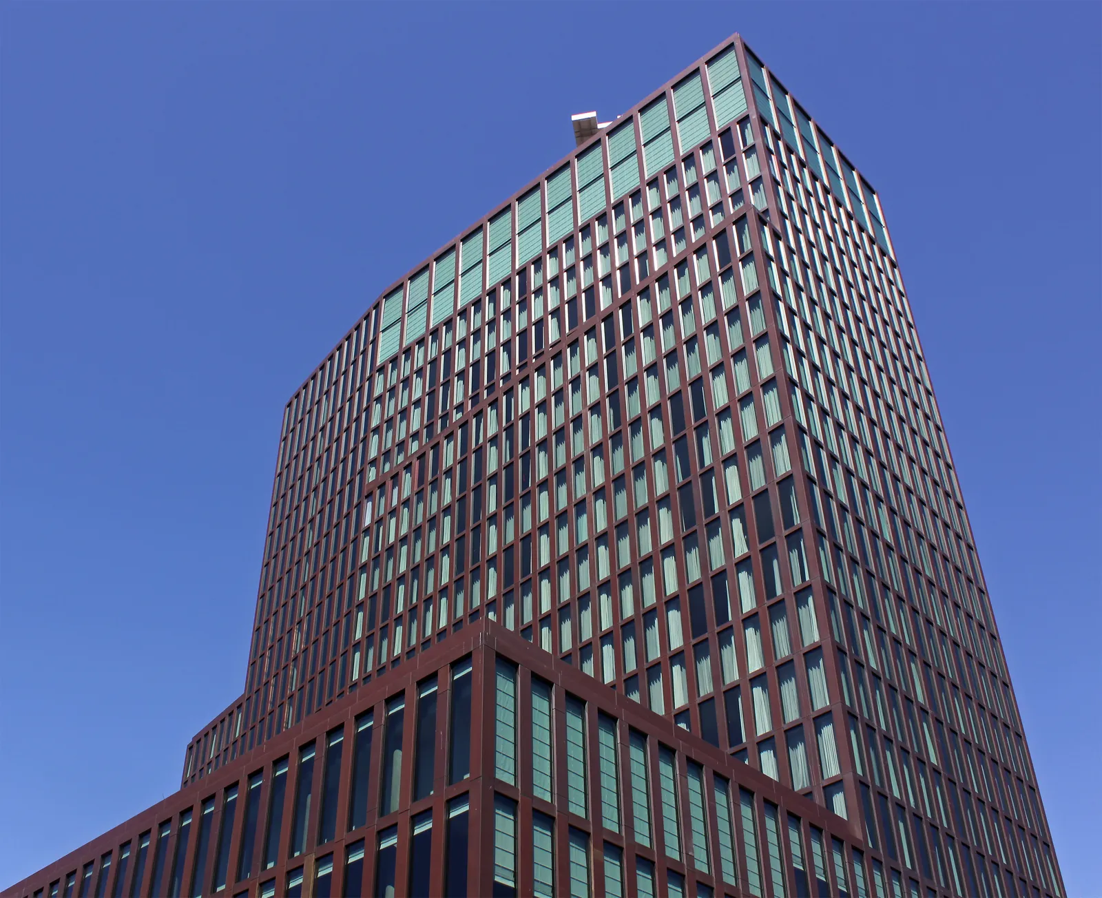 The dark red-brown glass and steel tower of the Empire Riverside Hotel in Hamburg rising against a clear blue sky