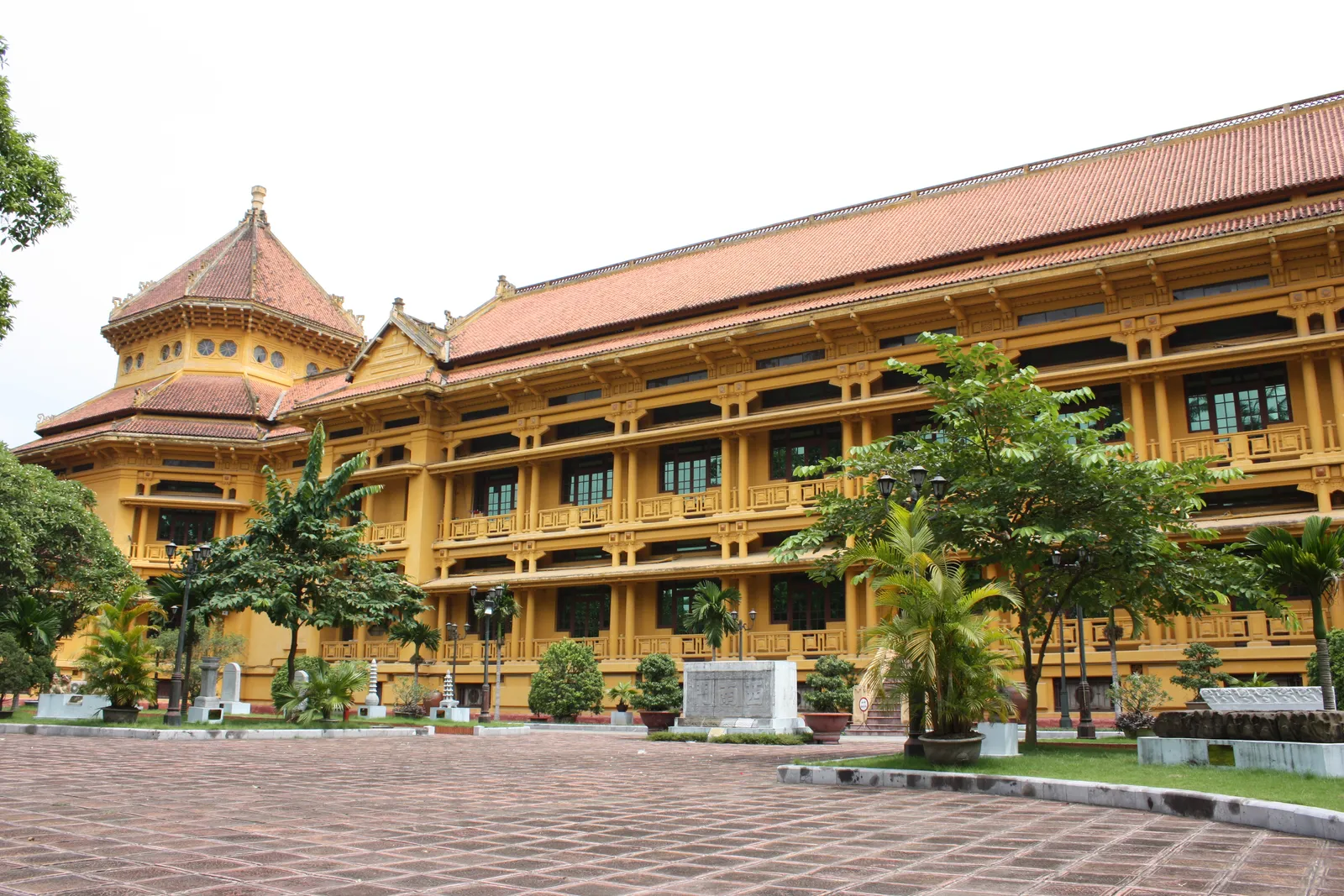 The Vietnam National Museum of History in Hanoi, a long ochre building with deep shaded verandas, latticed balustrades and a tiled octagonal tower at one end topped with a Vietnamese roof