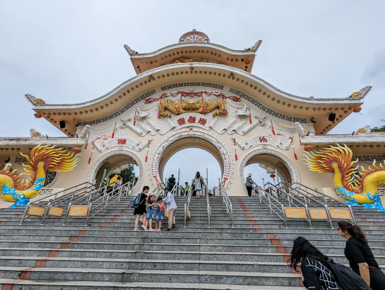 The entrance gate of Suoi Tien theme park outside Ho Chi Minh City, a broad flight of steps leading up to three arches under a curved tiled roof with gold dragons coiled around the flanking towers