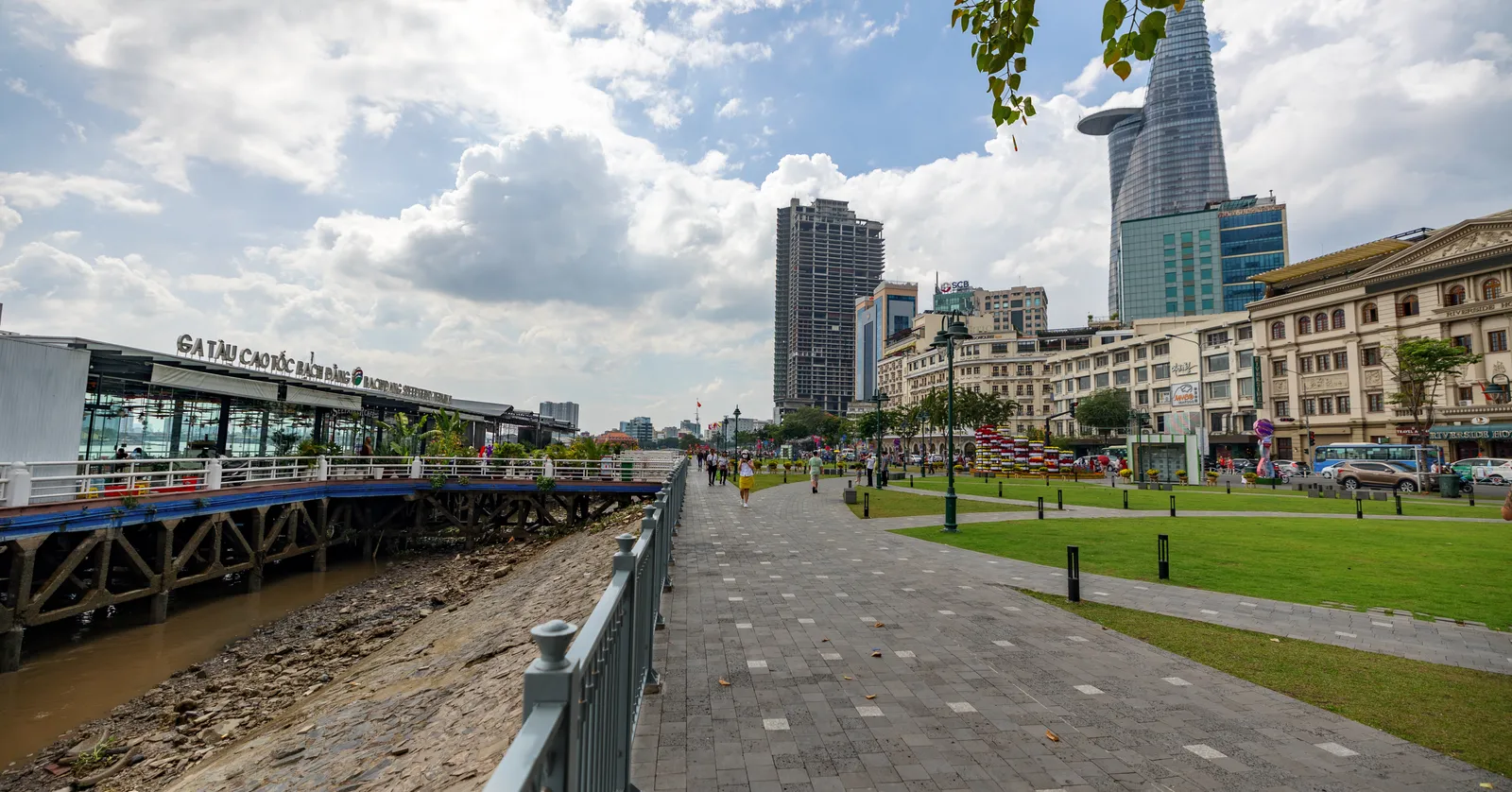 The paved riverside walk at Bach Dang in Ho Chi Minh City, the tapered Bitexco Financial Tower with its cantilevered helipad rising on the right and the waterbus pontoon on the left