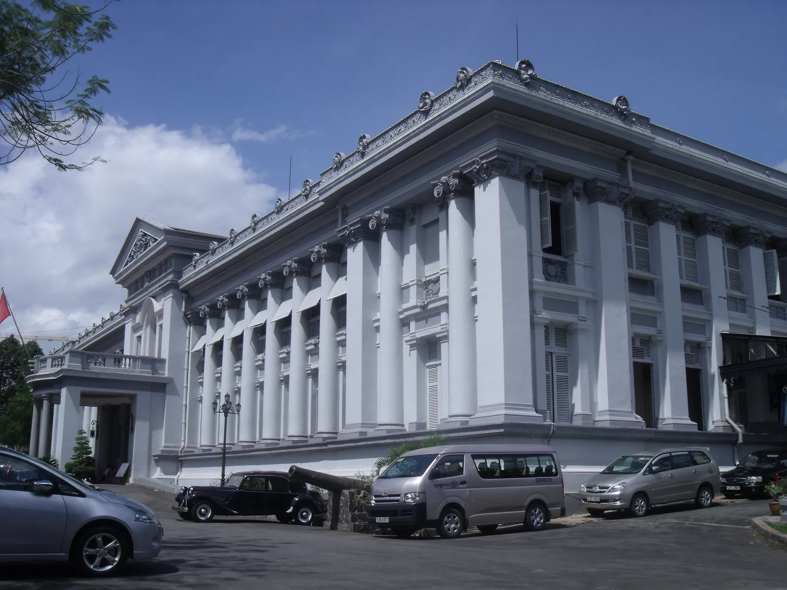 The white neoclassical frontage of the Museum of Ho Chi Minh City, formerly Gia Long Palace, its long colonnade of paired columns above a stepped entrance