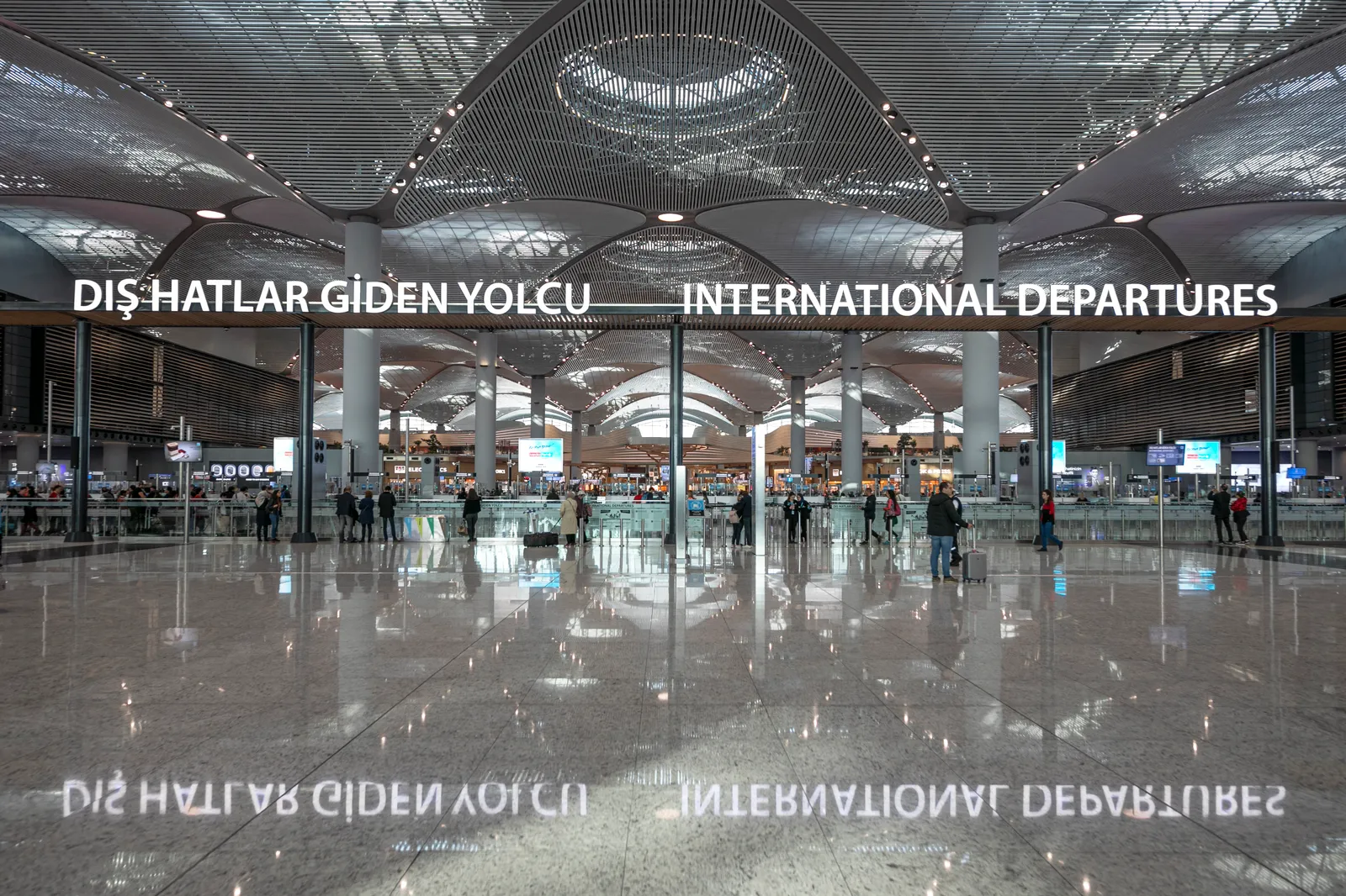 The international departures floor at Istanbul Airport, a wide polished hall under a ribbed vaulted ceiling, with the sign reading DIŞ HATLAR GİDEN YOLCU and INTERNATIONAL DEPARTURES above the glass doors